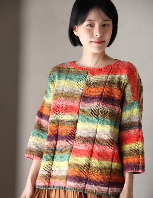 Woman wearing a colorful striped sweater against a plain background
