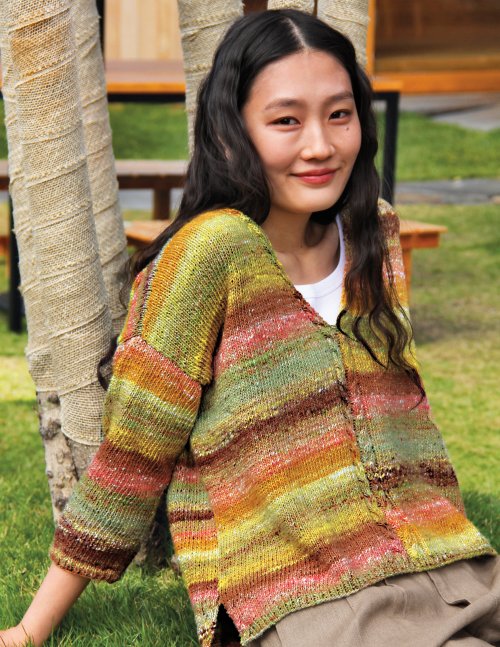 Woman wearing a colorful striped sweater sitting outdoors.